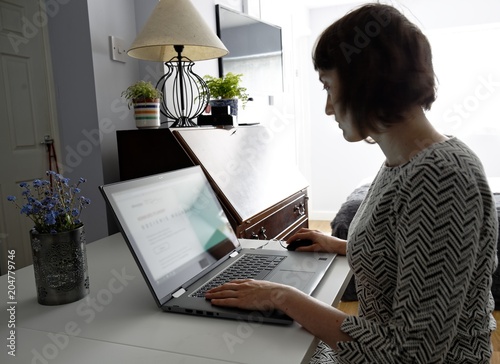 Young woman working in home office on laptop. Female silhouette using computer.
