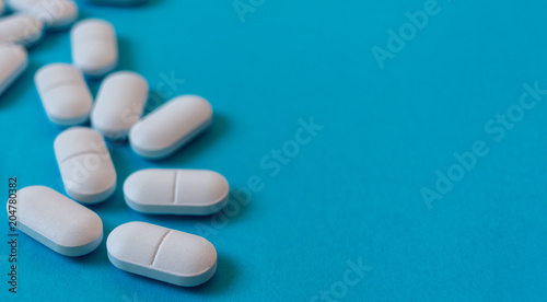 White Oval pills on blue background. Medicine and healthy