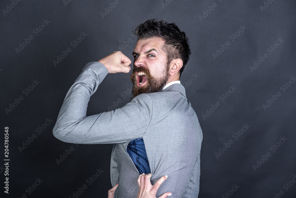 Angry guy bought counterfeit or fake brand. Man with beard wears jacket with hole on dark background. Hipster chose small size jacket, seam torn with female hands. Bad quality of clothes concept Angry guy bought counterfeit or fake brand. Man with beard wears jacket with hole on dark background. Hipster chose small size jacket, seam torn with female hands. Bad quality of clothes concept