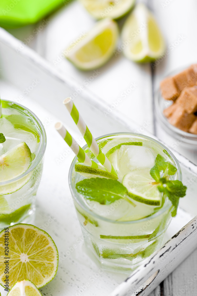 Summer refreshing cocktail mojito with lime and mint on white wooden vintage background.