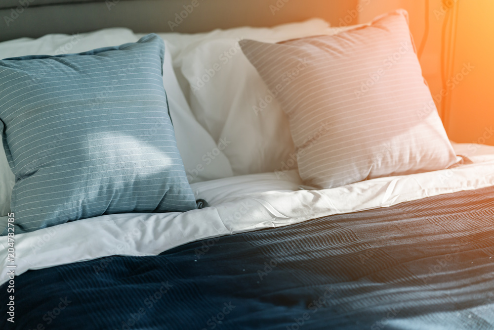 Bed maid-up with clean white pillows and bed sheets in bedroom. Close-up. Lens flair in sunlight. Bed maid-up with clean white pillows and bed sheets in bedroom. Close-up. Lens flair in sunlight.