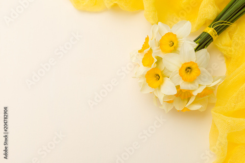 Fototapeta Naklejka Na Ścianę i Meble -  White daffodil bouquet with yellow textile decoration on pastel background with copy space.