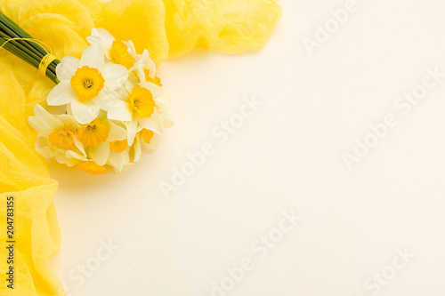 Fototapeta Naklejka Na Ścianę i Meble -  White daffodil bouquet with yellow textile decoration on pastel background with copy space.