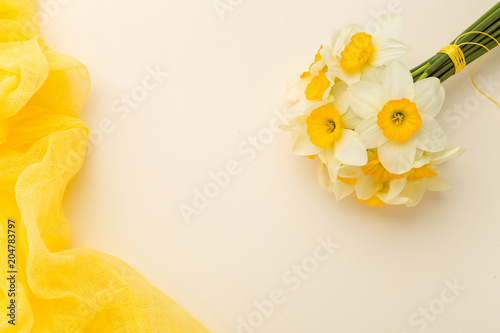 Fototapeta Naklejka Na Ścianę i Meble -  White daffodil bouquet with yellow textile decoration on pastel background with copy space.