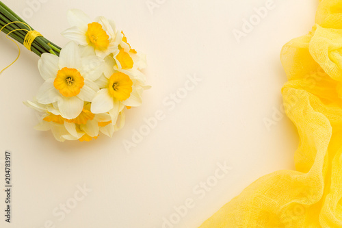 Fototapeta Naklejka Na Ścianę i Meble -  White daffodil bouquet with yellow textile decoration on pastel background with copy space.