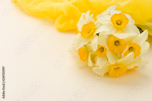 Fototapeta Naklejka Na Ścianę i Meble -  White daffodil bouquet with yellow textile decoration on pastel background with copy space.