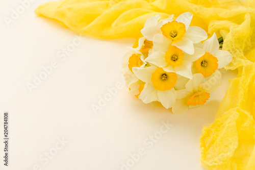 Fototapeta Naklejka Na Ścianę i Meble -  White daffodil bouquet with yellow textile decoration on pastel background with copy space.