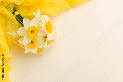 Fototapeta Naklejka Na Ścianę i Meble -  White daffodil bouquet with yellow textile decoration on pastel background with copy space.
