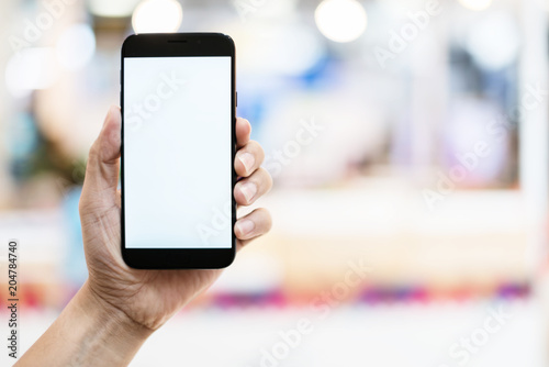 business communication ideas concept with hand hold white blank screen smartphone with blur bokeh mall background