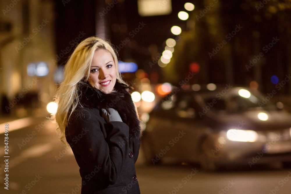 Fototapeta premium Beautiful, blonde woman in car lights in the night city.