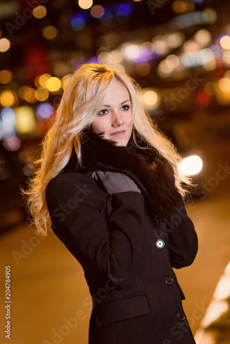 Beautiful  blonde woman in car lights in the night city.