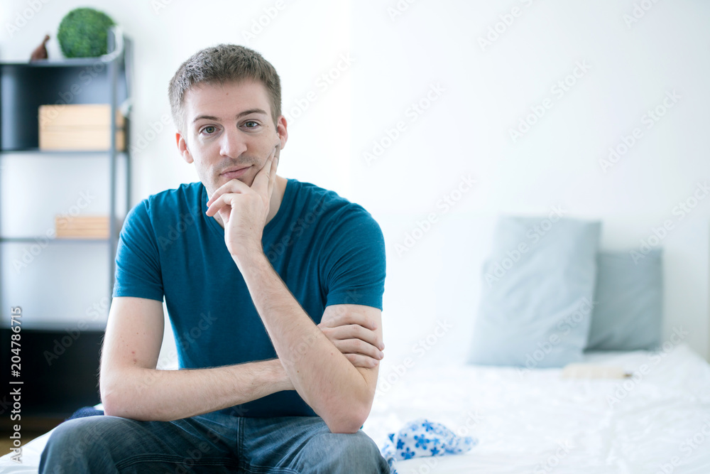 caucasian smart man waking up from sleep and sit on his bed on white room background caucasian smart man waking up from sleep and sit on his bed on white room background