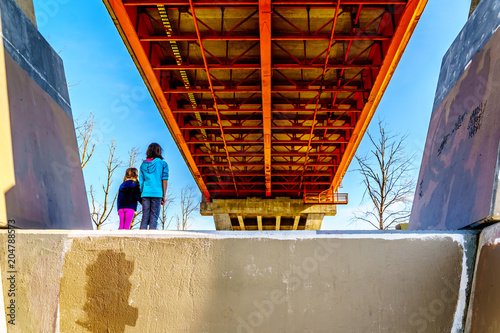 Two girls in awe of the massive Steel and Concrete structure of Mission Bridge over the Fraser River on Highway 11 between Abbotsford and Mission in British Columbia, Canada photo