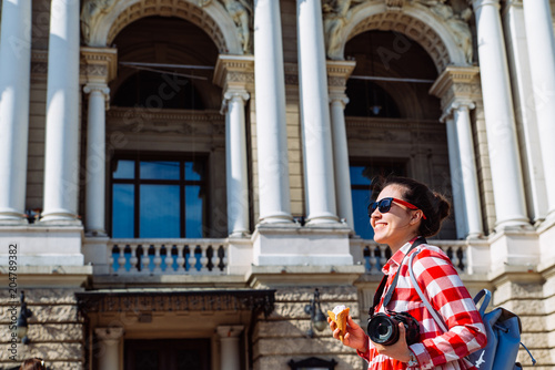 woman walking by city with camera and ice cream. copy space