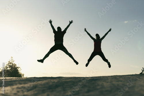 Two sportsperson silhouettes jumping