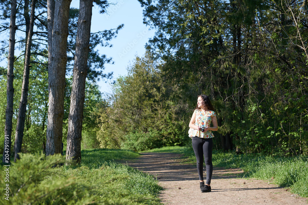 Obraz premium young girl walking in spring forest with camera and taking pictures
