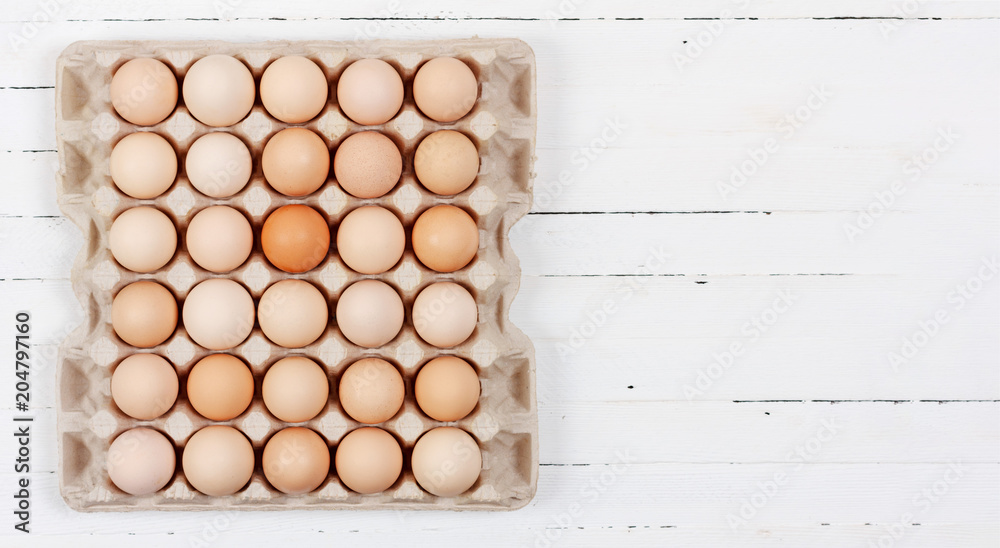the eggs in the carton boxes laying on white wooden background with copy space closeup