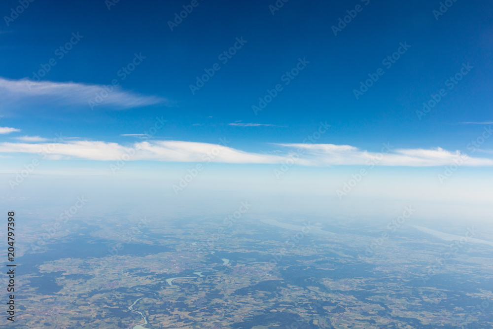 View from the airplane to the sky above the Alps mountains. Blue sky with clouds. Background.