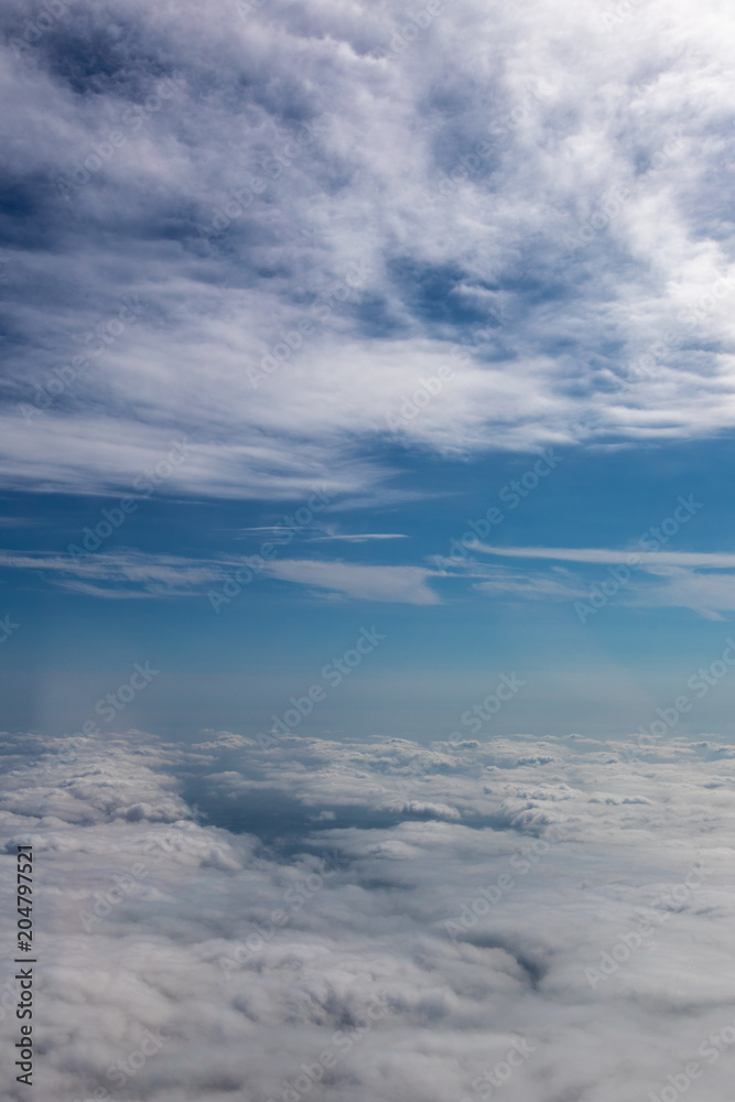 View from the airplane to the sky above the Alps mountains. Blue sky with clouds. Background.