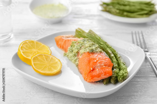 Plate with tasty fish and asparagus on table