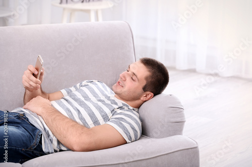 Young man with phone on sof...