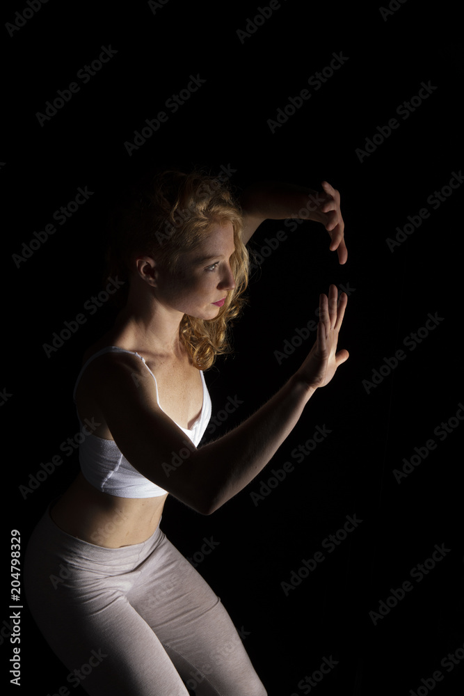Mujer joven realizando danza contemporánea en estudio con fondo negro Mujer joven realizando danza contemporánea en estudio con fondo negro