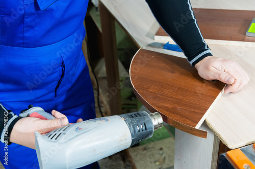 Professional carpenter at work dries a tree by a professional industrial hair dryer hand tool close-up of a carpentry and handicraft concept