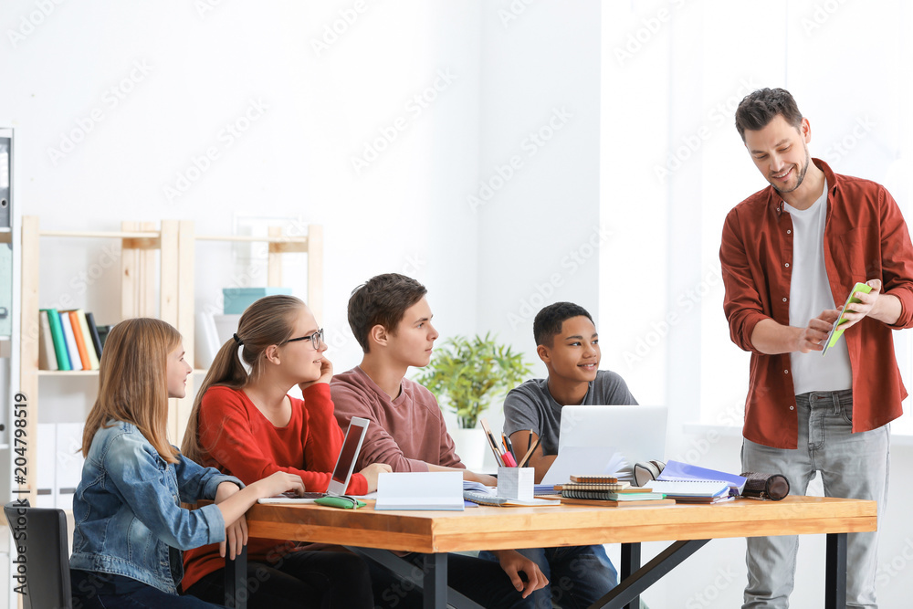 Group of teenagers doing homework with teacher in classroom Group of teenagers doing homework with teacher in classroom