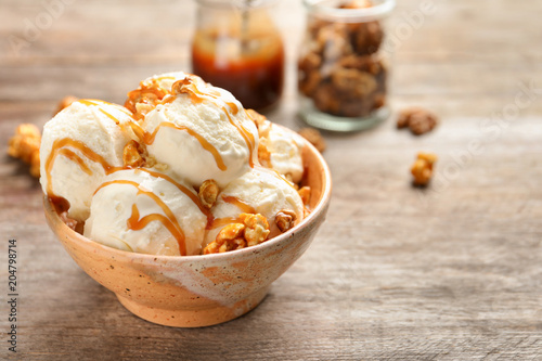 Bild auf Leinwand Tasty ice cream with caramel sauce and popcorn in bowl on wooden table