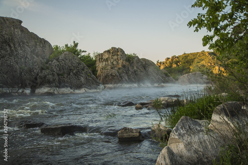 Small mountain river. Landscape with stream flowing between rocks. Water in mountains. River in fog
