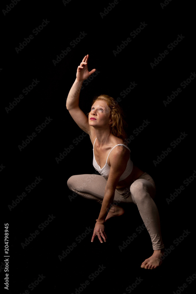 Mujer joven realizando danza contemporánea en estudio con fondo negro 