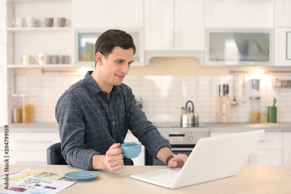 Portrait of confident young man with  laptop and cup at table