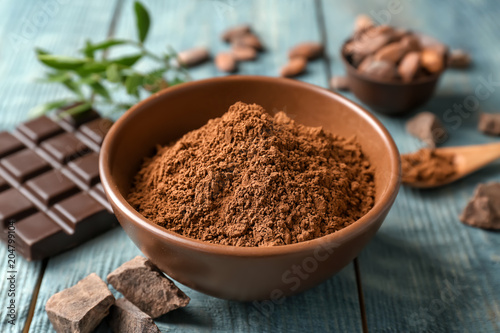 Composition with cocoa powder and chocolate bar on wooden background