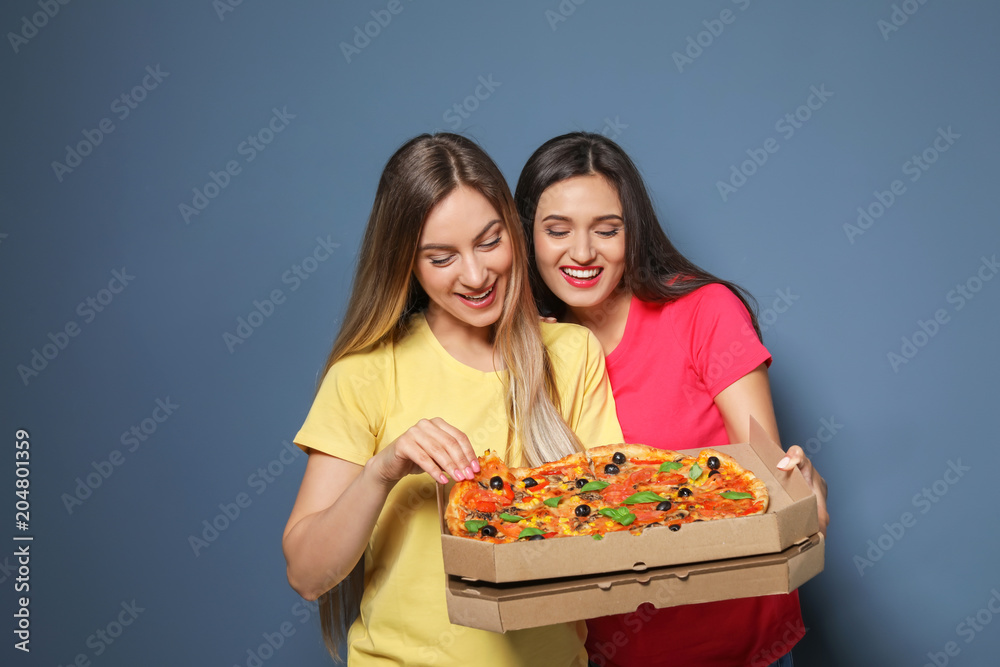 Attractive young women with delicious pizza on color background