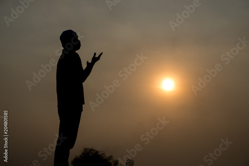 Silhouette Young asian muslim man praying on sunset Ramadan festival concept