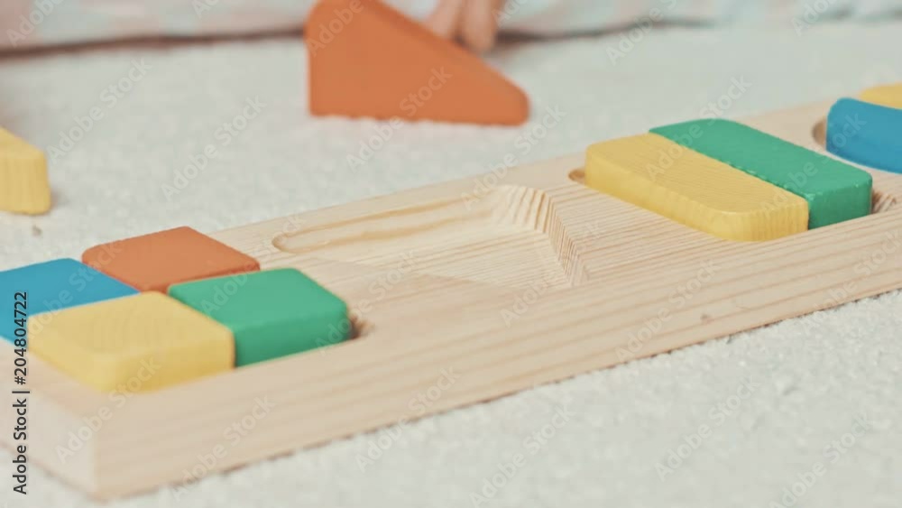Child plays with wooden toy baby sorter with geometric figures