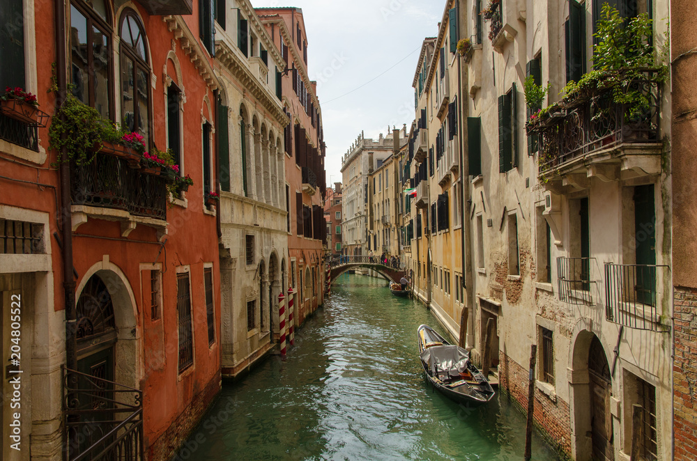 View of a canal of Venice with some boats and a sunny light, Italy