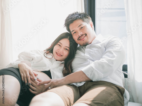 Asian man husband take care of his pregnant wife.Beautiful pregnant woman and her handsome husband are smiling while spending time together.