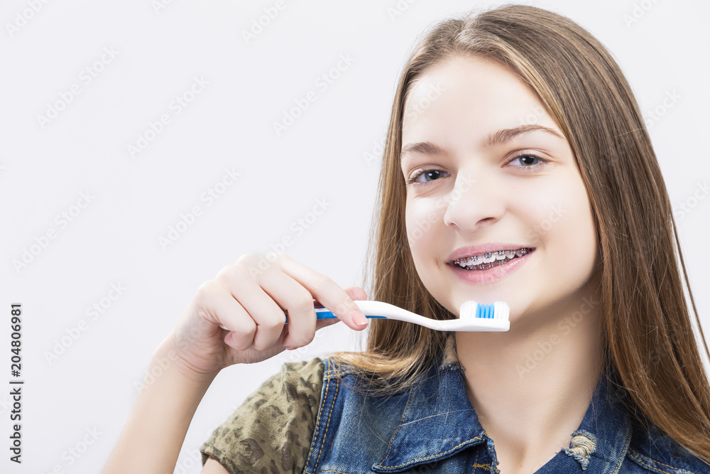 Dental Health Concepts. Portrait of Smiling Caucasian Teenage Girl with Teeth Brackets. Posing with Toothbrush Dental Health Concepts. Portrait of Smiling Caucasian Teenage Girl with Teeth Brackets. Posing with Toothbrush