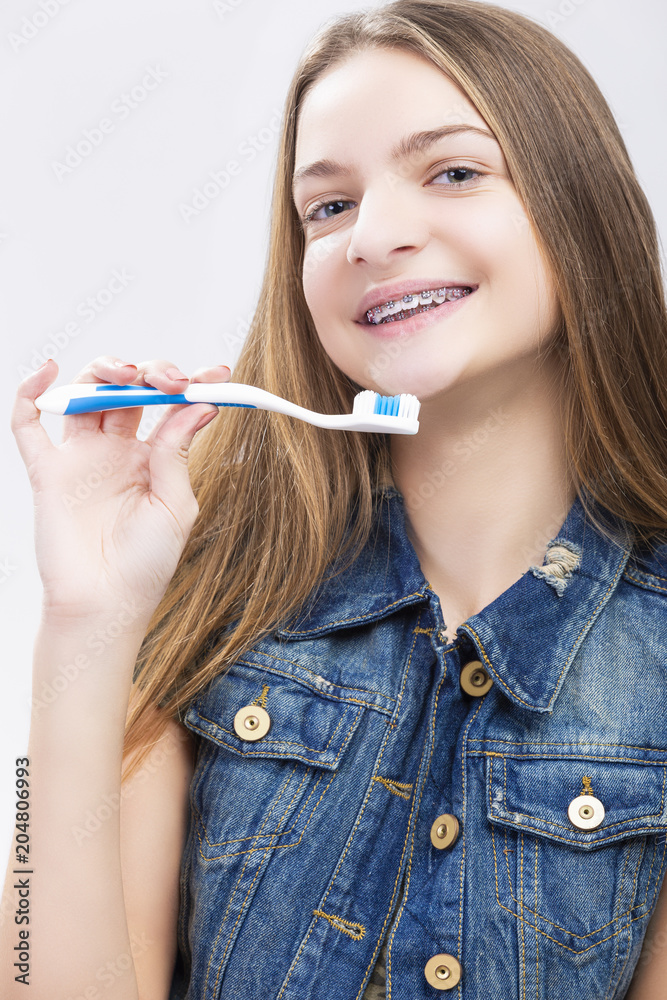 Dental Health Concepts. Portrait of Smiling Caucasian Teenage Girl with Teeth Brackets. Posing with Toothbrush. Dental Health Concepts. Portrait of Smiling Caucasian Teenage Girl with Teeth Brackets. Posing with Toothbrush.
