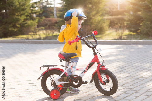 Happy kid boy of 3 years having fun in spring park with red bicycle on sunny day. Active child wearing bike helmet. Safety, sports, lifestyle, leisure with children © uv_group