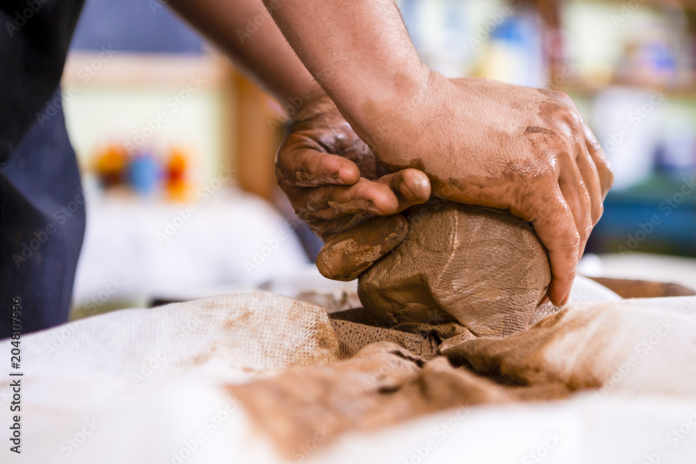 Concepts of Ceramist in Workshop. Closeup of Working Hands of Male Potter Professional Making a Clay Lump in Studio. Concepts of Ceramist in Workshop. Closeup of Working Hands of Male Potter Professional Making a Clay Lump in Studio.