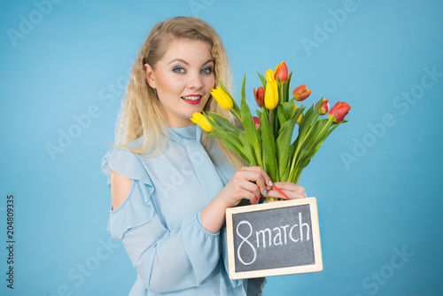 Woman holds tulips, board with text 8 march