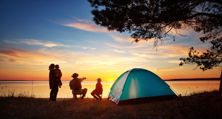 Family resting with tent in nature at sunset