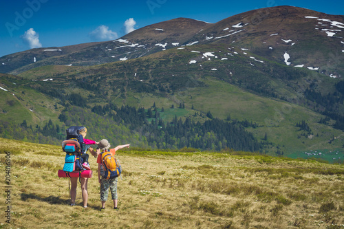 Family of hikers in a spring mountain valley © Bashkatov
