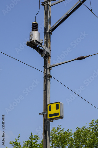 Electrical pole by the railway with train yellow signal.