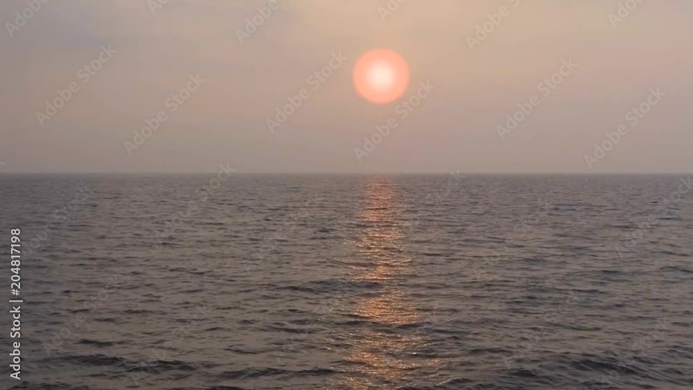 Tropical sunset. The sun sets over the ocean, the sea waves in the evening light Tropical sunset. The sun sets over the ocean, the sea waves in the evening light