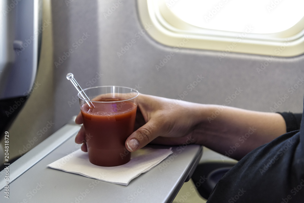 Obraz premium Glas mit Tomatensaft an Bord eines Flugzeugs