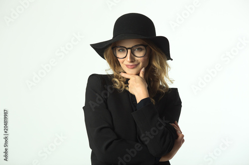 beautiful young girl with glasses and hat, wearing a black jacket on a white background © Alexandr