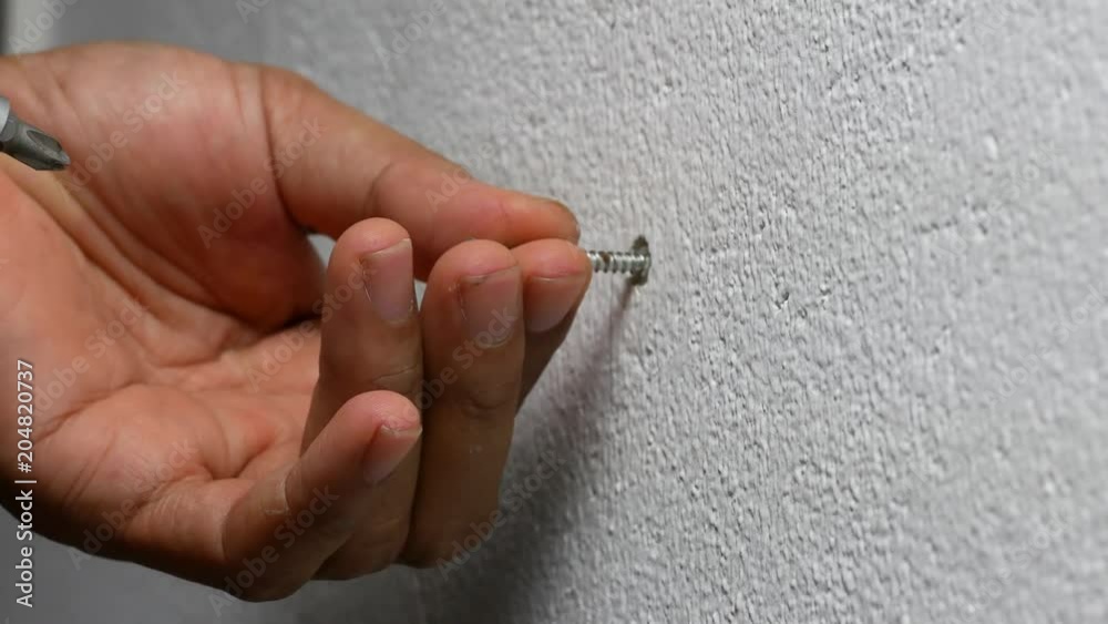 man hand using electric screwdriver to tighten the screw into plastic plug , wall anchors in the